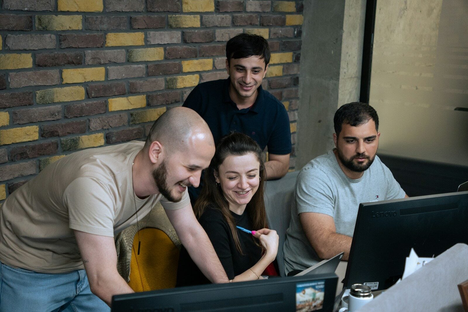 A group of people sitting around a laptop computer